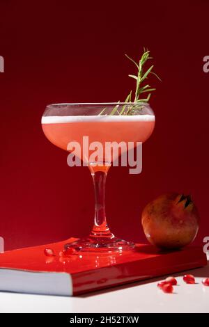 Festive isolated red cocktail. Pomegranate drink with white egg and rosemary Stock Photo
