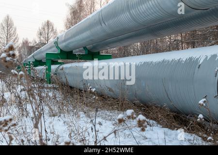 central heating pipes in a protective metal thermal insulation jacket laid above the ground on a cold winter day Stock Photo