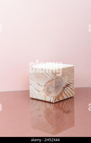 wooden cube with mirror reflection, pink background Stock Photo