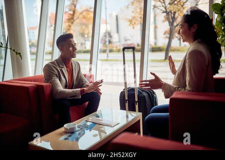 Smiling man and woman sitting in lobby of a hotel Stock Photo