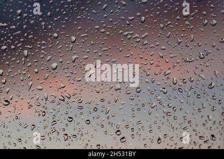 After rain. The window pane is covered on the outside with drops of water. There are dark clouds in the background. Stock Photo