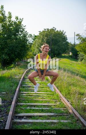 nimble girl jumping on the railroad tracks