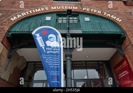 Hamburg, Germany. 06th Nov, 2021. A banner with the inscription ìHere we vaccinate!î stands in front of the entrance to the International Maritime Museum Hamburg. A Corona vaccination appointment of the German Red Cross took place at the museum. Credit: Georg Wendt/dpa/Alamy Live News Stock Photo