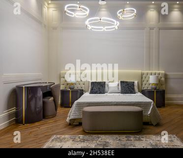 Interior of modern room with comfortable bed and bedside tables with lamps under ceiling with creative chandeliers  Stock Photo