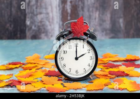 Alarm clock with autumn leaves - daylight savings time concept Stock Photo
