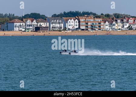 Jet Ski riders jetting past the seafront of Southend on Sea, essex, UK, viewed from Southend Pier out in the Thames Estuary. Beach, coast, properties Stock Photo