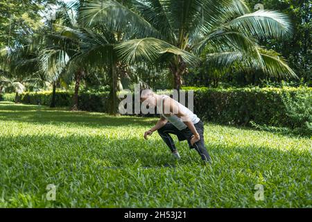 Sporty active young man in sportswear doing sport exercises in the park. Muscular fit man doing exercises outdoors. Healthy lifestyle concept, sport Stock Photo