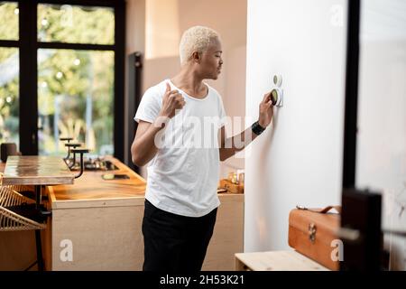 Latin man choosing temperature on thermostat Stock Photo