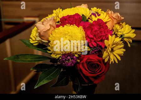 Beautiful flower arrangement in yellows and reds in a glass vase. Stock Photo