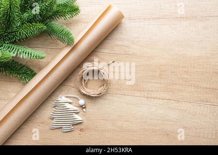 Gold striped Christmas toy in the form of a Christmas tree, a roll of kraft paper and a spruce branch on a wooden background with copy space, flat lay Stock Photo