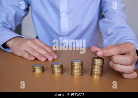 Businessman stacking coins on table, business growth concept. Hand puts coin to stack. Stock Photo