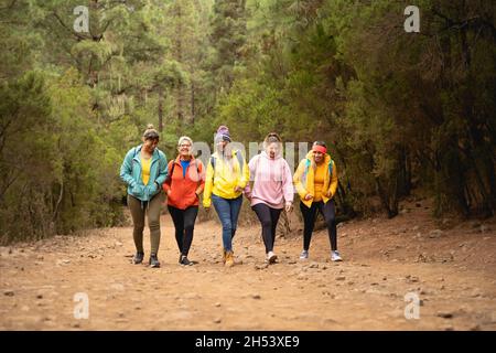 Group of women with different ages and ethnicities having fun walking in foggy forest - Adventure and travel people concept Stock Photo