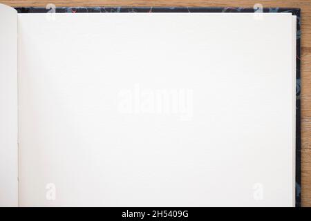 Notebook with plain white paper and hardback open on a wooden desk Stock Photo