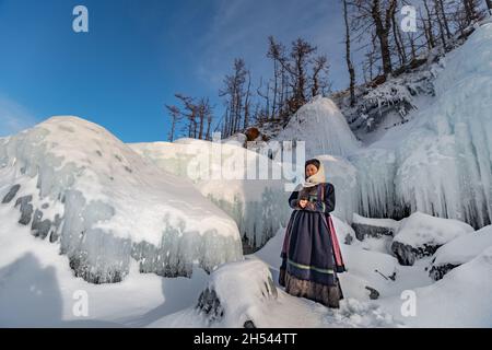 A Buryat girl standing on the icy cost on a little island on Baikal Lake in winter time Stock Photo