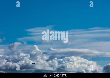 silhouette of an airplane flying over the city against the background of cumulus clouds Stock Photo
