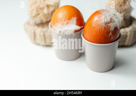 Fresh free range eggs with natural feathers in egg cups, eggs in woolen caps, funny food Stock Photo