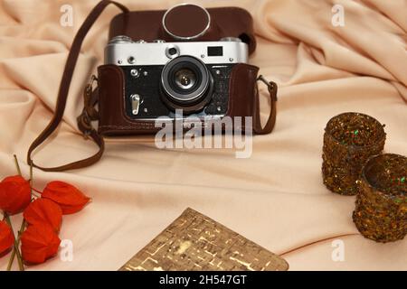 Flatlay. Film camera in case, notebook, fisalis and candlesticks lie on a light beige background. Stock Photo