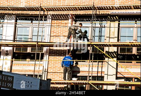 Builders carry out finishing works of the facade on the scaffolding Stock Photo