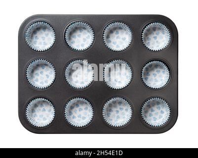 Muffin cake pan with paper baking cups isolated on a white background. Empty 12-cup muffin non-stick baking dish tray with paper corrugated molds. Stock Photo