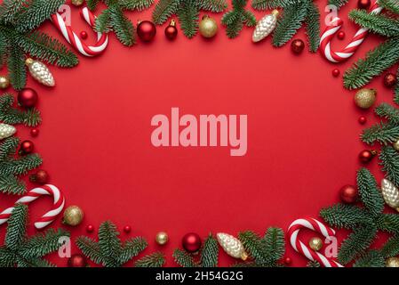 Red Christmas background with decorative frame of Christmas tree ornaments and fir branches Stock Photo