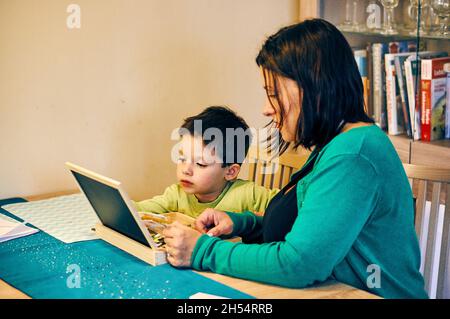 POZNAN, POLAND - Nov 12, 2017: A Polish Caucasian woman and a boy drawing on a chalkboard on the table at home Stock Photo