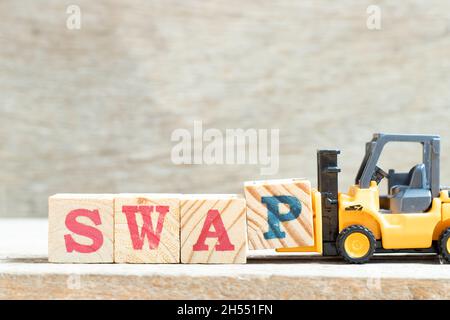 Toy forklift hold letter block p to complete word swap on wood background Stock Photo