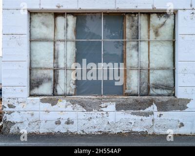 Insulation showing through windows on an old concrete building Stock Photo