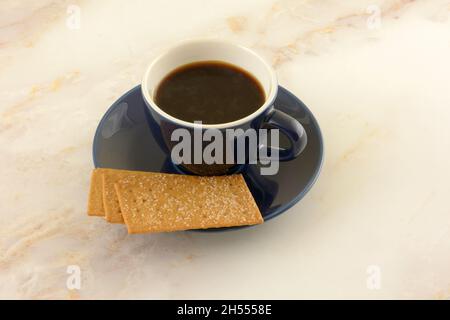 Coffee biscuits and coffee in blue and white demitasse cup with saucer on table Stock Photo