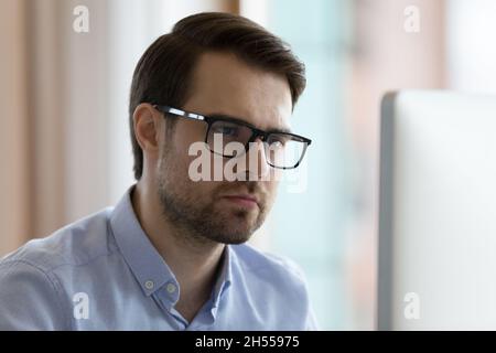 Pensive serious young businessman working on computer. Stock Photo
