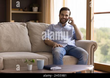 Smiling handsome young man holding cellphone conversation. Stock Photo