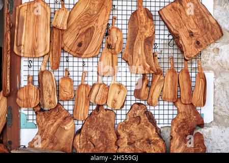 Authentic handmade wooden cutting boards hanging at the wall of a store. Stock Photo