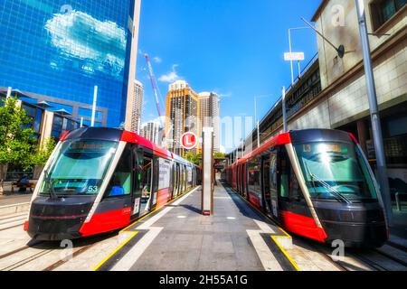 Two light rail tram trains at Circuar Quay end stop in Sydney city CBD on a sunny day - modern urban eco transport. Stock Photo