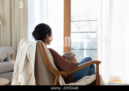 Calm Indian woman relax on comfy armchair with tea cup Stock Photo