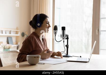 Woman wear headphones recording podcast on laptop talks using microscope Stock Photo