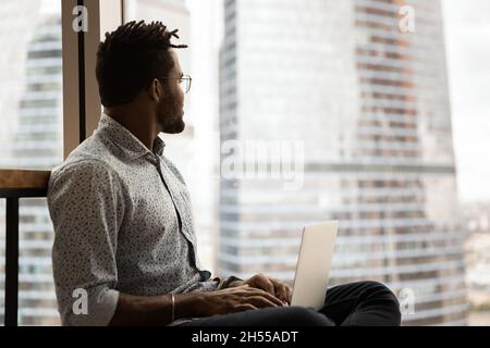Dreamy smart young african american freelancer working on computer. Stock Photo