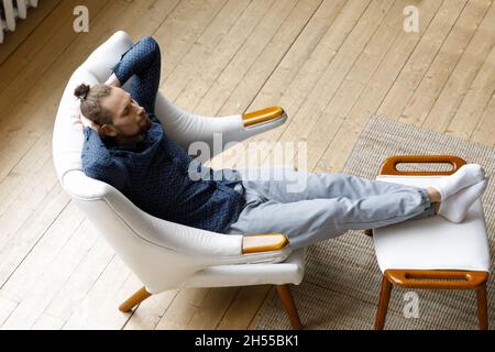 Relaxed young hipster man sleeping in cozy armchair. Stock Photo
