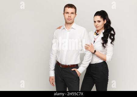 Concept of partnership in business, a young man and woman standing against a gray background Stock Photo