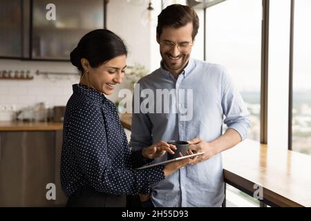 Happy diverse employees discussing online project on touchpad. Stock Photo