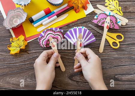In the hands of a child craft Thanksgiving toy stics puppets turkey. Childrens art project, handmade, crafts for kids. Stock Photo