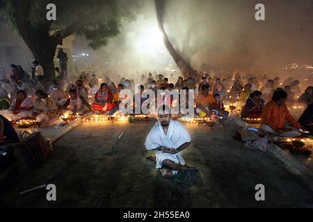 NOVMBER 06,2021,DHAKA,BANGLADESH-Thousands of Hindu devotees sit with Prodip and pray to God in front of Shri Shri Lokanath Brahmachari Ashram temple during the religious festival Kartik Brati, also known as Rakher Upobash in Dhaka, Bangladesh. Every year thousands of Hindu devotees gather in front of Shri Shri Lokenath Brahmachari Ashram temple for the Kartik Brati or Rakher Upobash religious festival in Barodi, Near Dhaka, Bangladesh. Devotees sit in front of candles light (named locally as Prodip). Lokenath Brahmachari who is called Baba Lokenath was an 18th Century Hindu saint and philosop Stock Photo