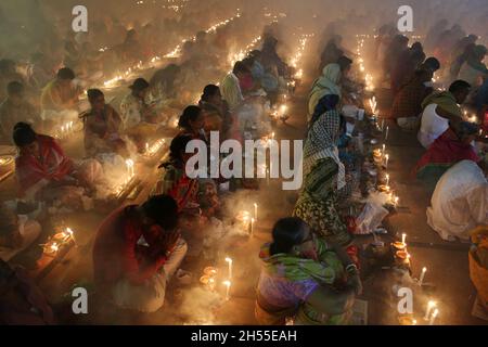 NOVMBER 06,2021,DHAKA,BANGLADESH-Thousands of Hindu devotees sit with Prodip and pray to God in front of Shri Shri Lokanath Brahmachari Ashram temple during the religious festival Kartik Brati, also known as Rakher Upobash in Dhaka, Bangladesh. Every year thousands of Hindu devotees gather in front of Shri Shri Lokenath Brahmachari Ashram temple for the Kartik Brati or Rakher Upobash religious festival in Barodi, Near Dhaka, Bangladesh. Devotees sit in front of candles light (named locally as Prodip). Lokenath Brahmachari who is called Baba Lokenath was an 18th Century Hindu saint and philosop Stock Photo