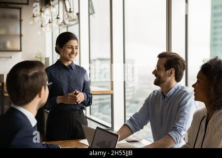 Happy indian team leader holding meeting with diverse colleagues. Stock Photo