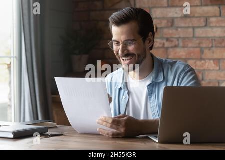 Excited male manager read paper document with data in graphs Stock Photo