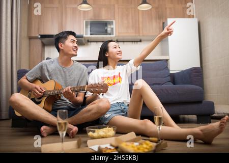 Happy couple playing guitar in the living room Stock Photo