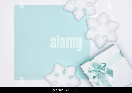 Gift box with white snowflake decorations top view. Copy space.  Winter holidays pastel cyan background Stock Photo
