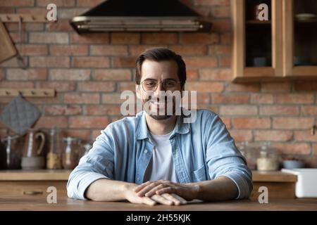 Portrait of happy young man sit at table in kitchen Stock Photo