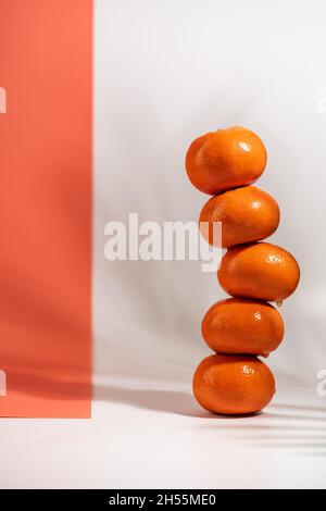 Stacked tangerines isolated on white and orange background. Healthy eating. Minimalism and balance concept with bright shadows Stock Photo