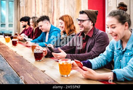 Multicultural addicted friends drinking beer and having fun with mobile smart phones at brewery pub restaurant - Social gathering concept Stock Photo