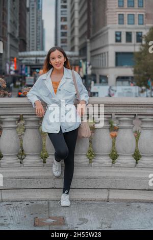 A shallow focus of a pretty happy smiling Caucasian female leaning on a decorative barrier outdoors Stock Photo