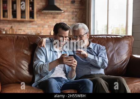 Retired male and his grown son making videocall on smartphone Stock Photo